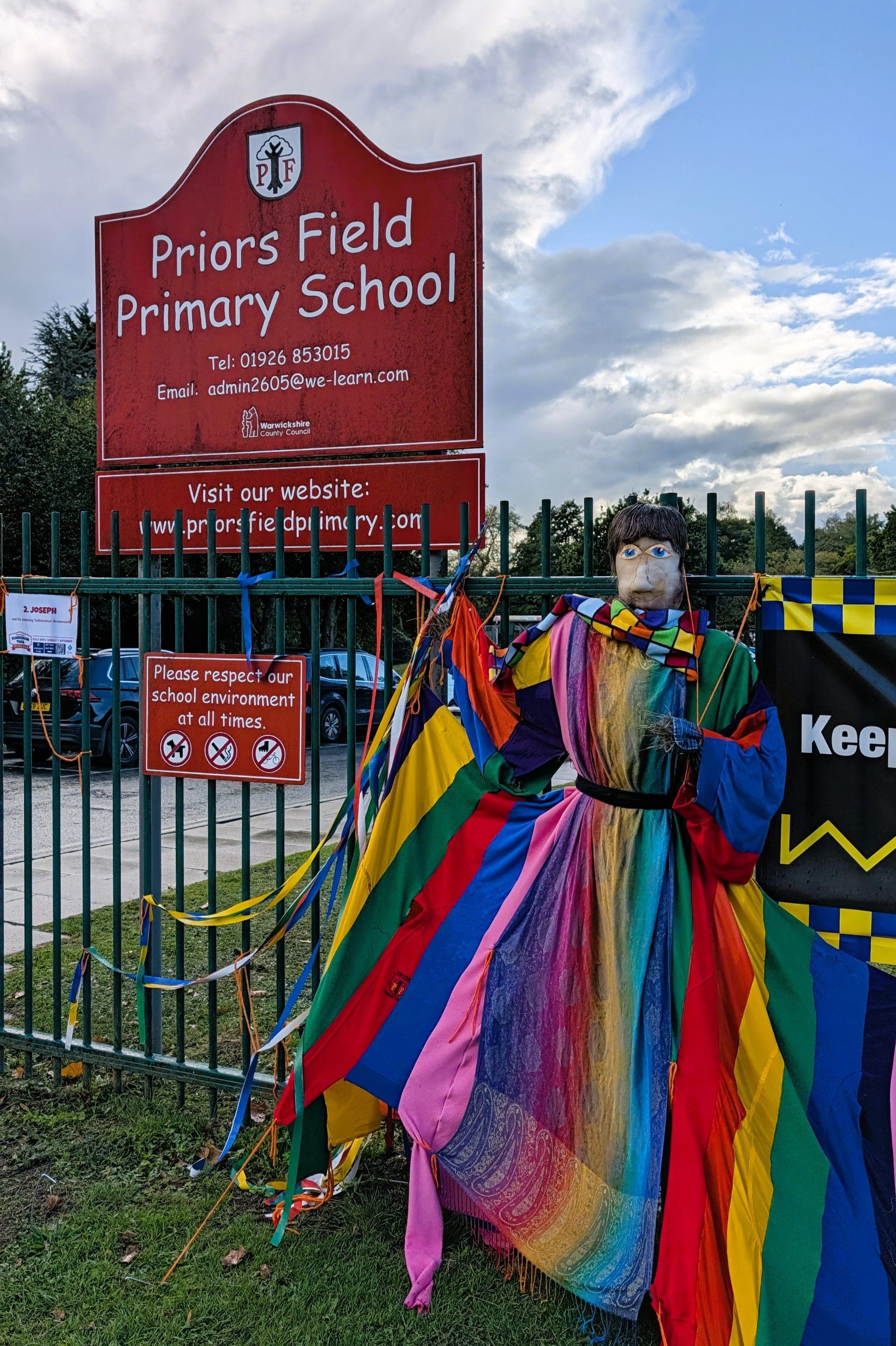 Scarecrow Joseph wears his amazing technicolour dreamcoat in front of the railings outside Priors Field Primary School.